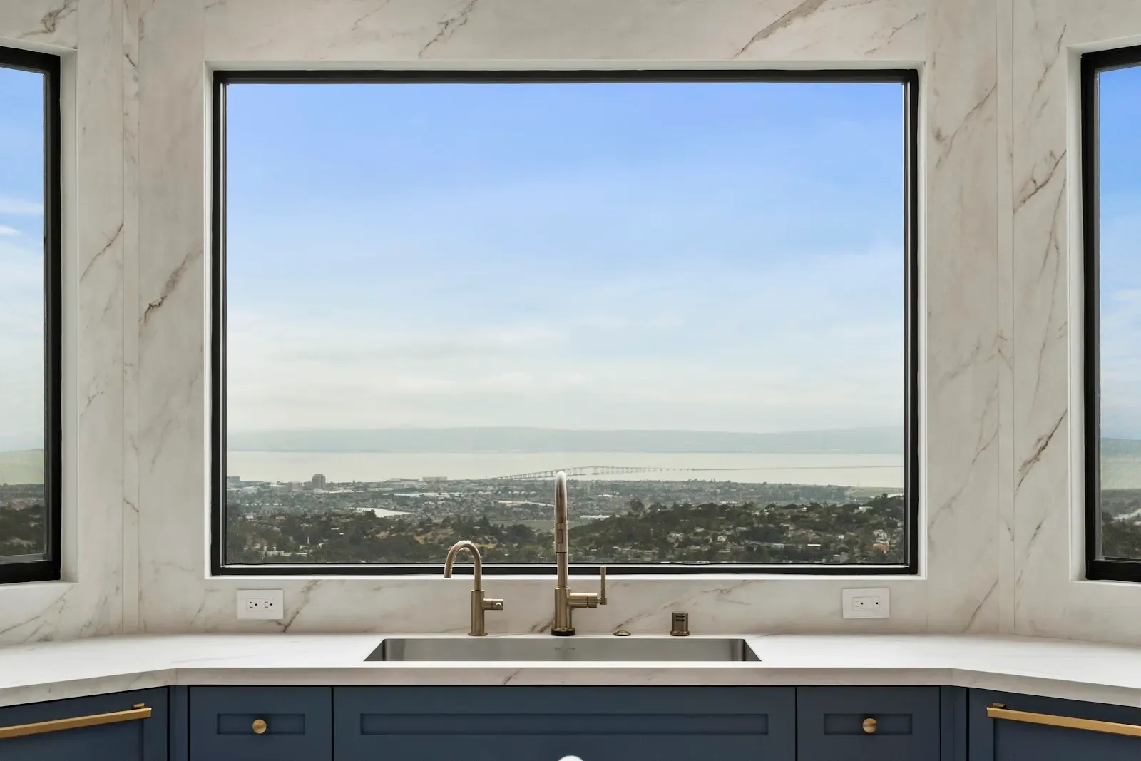 Kitchen sink framed by a picture window with a sweeping bay view