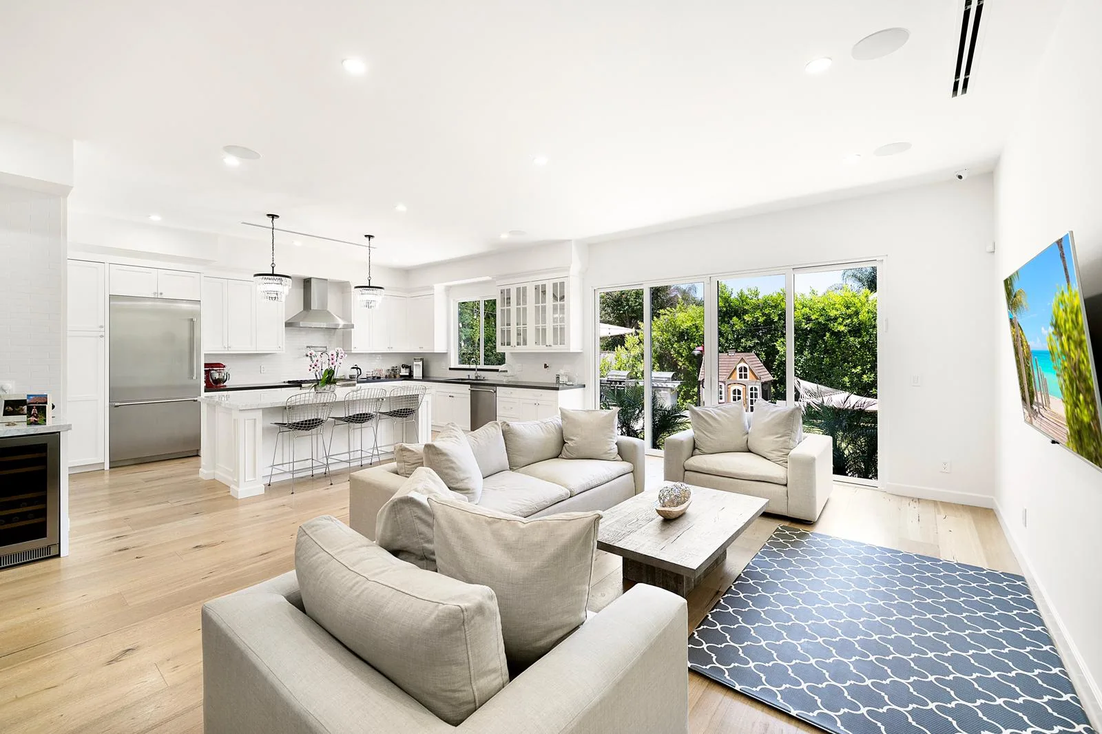Open-concept addition with a white kitchen island flowing into a family room with sliding doors to the backyard