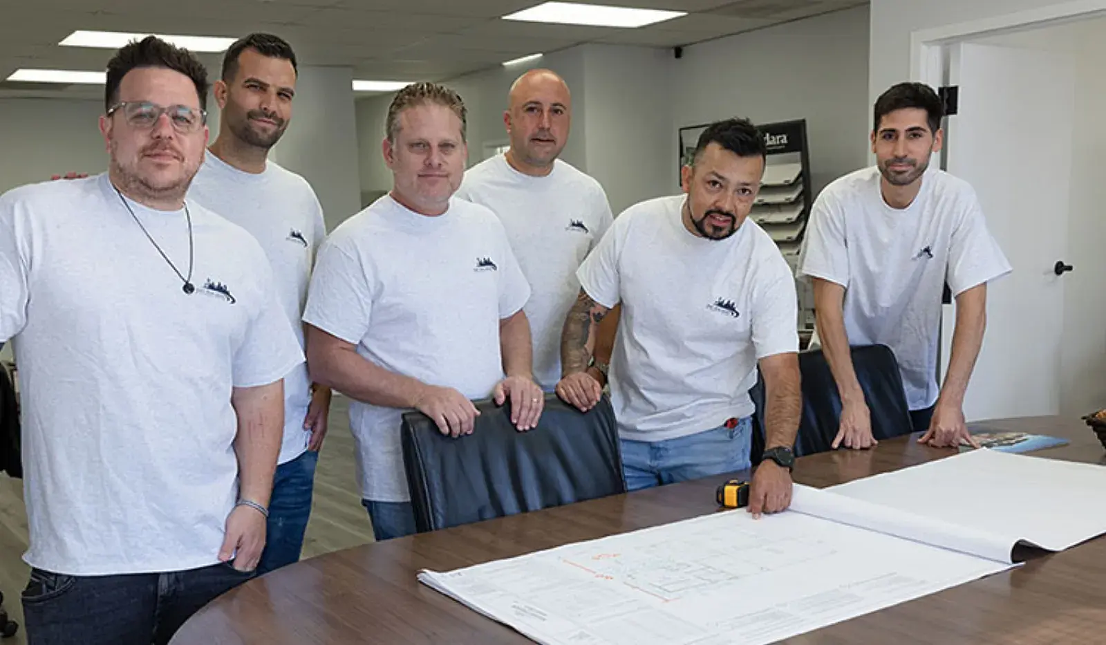 The Bay Builders team gathered around a set of plans at the San Jose office